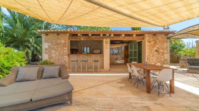 Covered outdoor terrace of the Felanitx finca with lounge, dining table and rustic stone bar