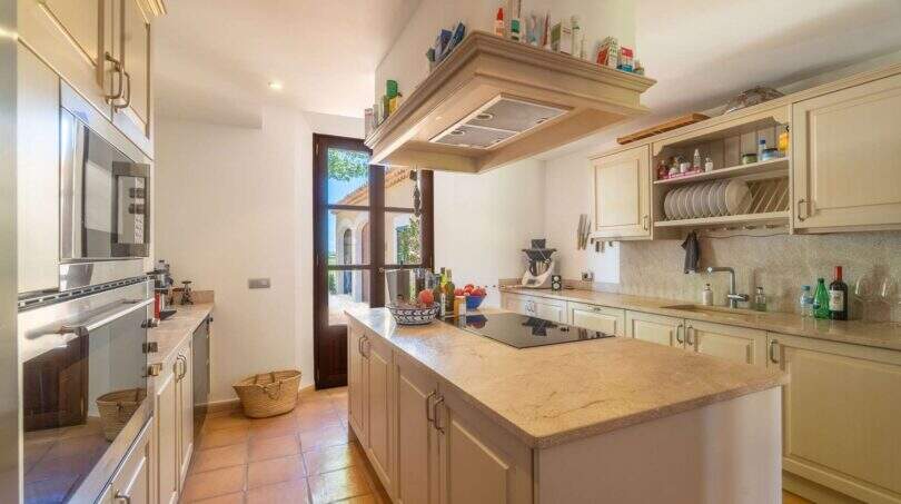 Kitchen of the Felanitx finca with cooking island, granite countertops, built-in appliances and terracotta floor