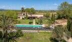 Aerial view of an exclusive finca in Felanitx with pool, garden facilities, palm trees and vineyards in the background.