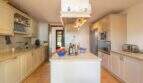 Bright country kitchen with kitchen island, built-in appliances and terracotta floor in exclusive Felanitx finca