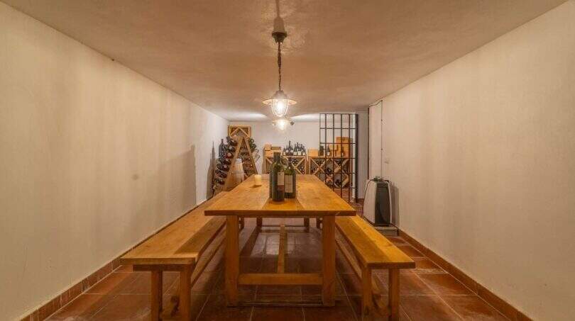 Wine cellar of the Felanitx finca with wooden table, benches, wine racks and atmospheric lighting
