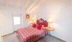Schlafzimmer mit rotem Doppelbett, Holzbalkendecke und Pop-Art-Wandbild im Stadthaus Felanitx