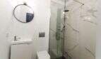Modernes Badezimmer mit Marmordusche, rundem Spiegel und wandhängendem WC im Stadthaus Felanitx