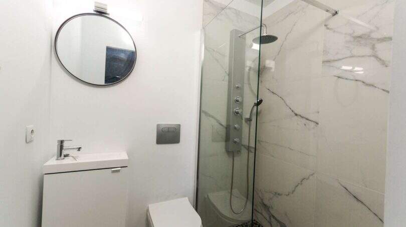 Modernes Badezimmer mit Marmordusche, rundem Spiegel und wandhängendem WC im Stadthaus Felanitx
