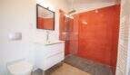 Modernes Badezimmer mit roter Duschfliese, Glastrennwand, Wandtoilette und weißem Waschtisch im Stadthaus Felanitx