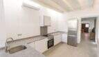 Moderne Küche mit Granitarbeitsplatte, Einbauofen und Kühlschrank im Stadthaus Felanitx