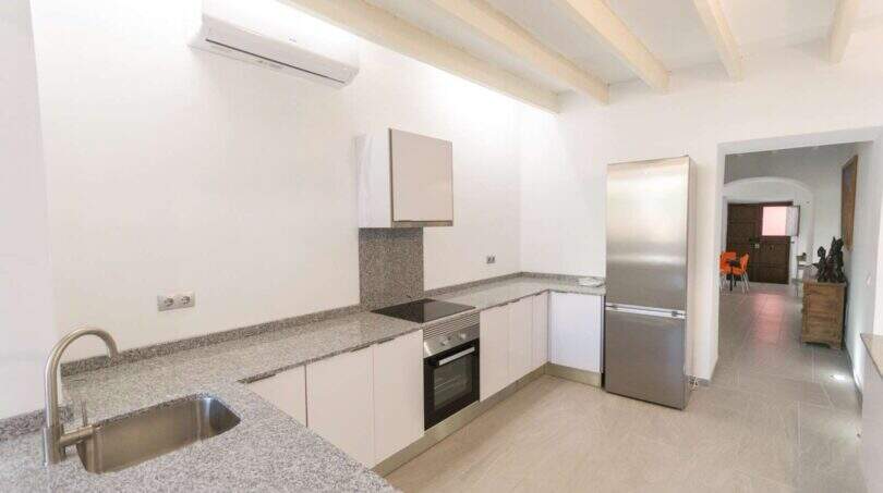 Moderne Küche mit Granitarbeitsplatte, Einbauofen und Kühlschrank im Stadthaus Felanitx