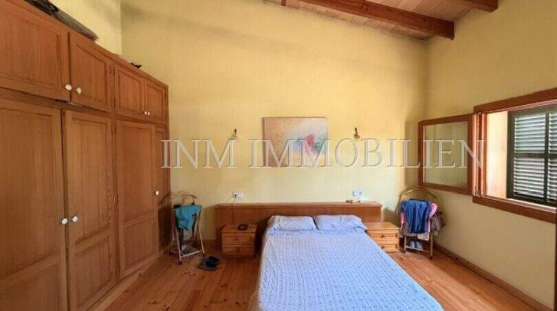 Helles Schlafzimmer der Finca in Llucmajor mit Holzboden, Einbauschrank und Holzbalkendecke.