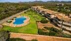 Luftaufnahme Wohnanlage Porto Colom mit großem Pool, gepflegten Grünanlagen und mediterranen Terrassenhäusern umgeben von Pinienwald.