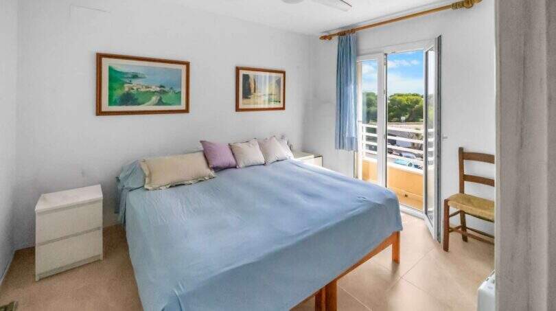 Helles Schlafzimmer der Wohnung in Porto Colom mit Doppelbett, Deckenventilator und Balkonzugang mit Meerblick