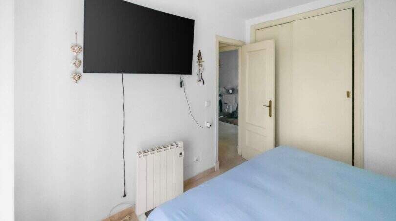 Schlafzimmer der Wohnung in Portocolom mit Doppelbett, Wand-TV und Heizkörper