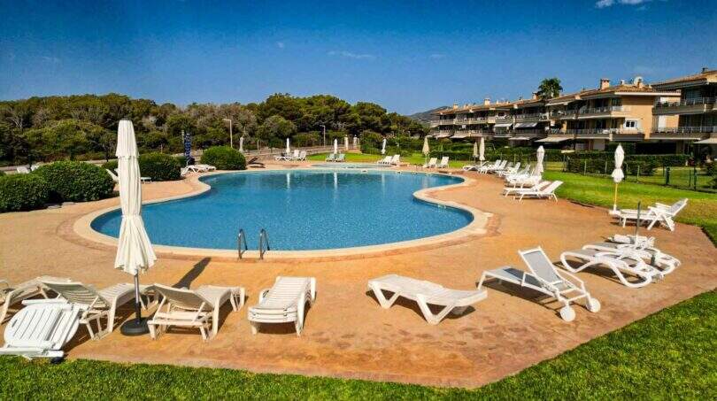 Großer Außenpool mit Liegestühlen und Sonnenschirmen der Wohnanlage in Porto Colom, Mallorca