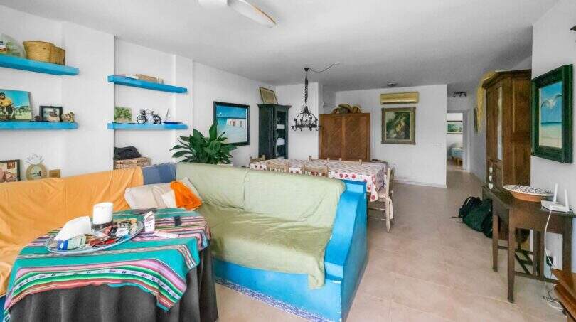 Helles Wohnzimmer der Wohnung in Porto Colom mit buntem Sofa, Esstisch, Deckenventilator und Klimaanlage