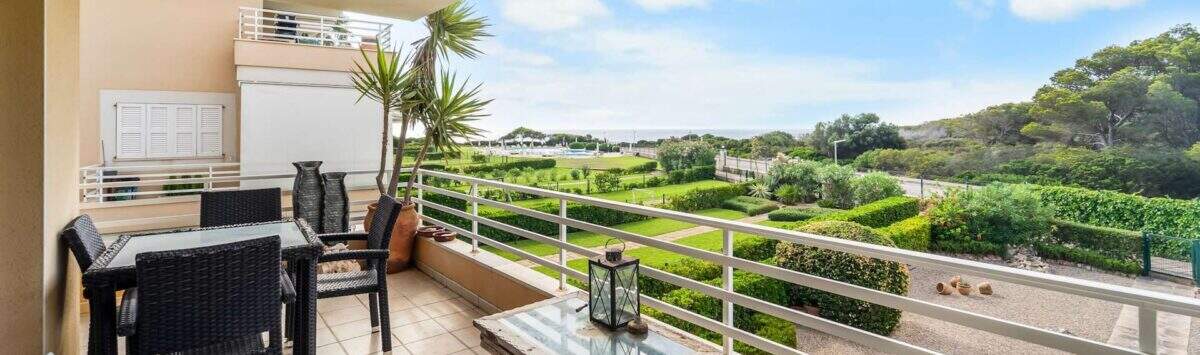 Geräumige Terrasse der Wohnung in Porto Colom mit Rattanmöbeln, Gartenblick und Meerblick im Hintergrund.