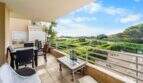 Geräumige Terrasse der Wohnung in Porto Colom mit Rattanmöbeln, Gartenblick und Meerblick im Hintergrund.