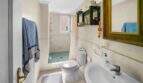 Helles Badezimmer der Wohnung in Porto Colom mit Dusche, WC, Waschbecken und Handtuchhalter.
