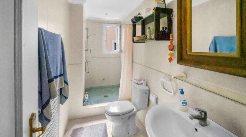 Helles Badezimmer der Wohnung in Porto Colom mit Dusche, WC, Waschbecken und Handtuchhalter.