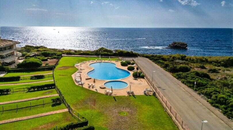 Luftaufnahme Pool-Anlage mit Meerblick, gepflegter Rasen, Liegestühle, Wohnung in Porto Colom
