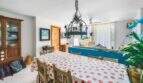 Esszimmer der Wohnung in Porto Colom mit gepunktetem Tischtuch, Schmiedeeisen-Kronleuchter und blauer Raumteiler-Wand.
