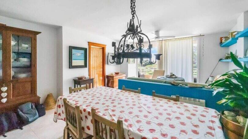 Esszimmer der Wohnung in Porto Colom mit gepunktetem Tischtuch, Schmiedeeisen-Kronleuchter und blauer Raumteiler-Wand.