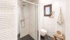 Modernes Badezimmer mit Glasdusche, Marmorfliesen, Handtuchheizung und rustikalem Holzhocker in Felanitx