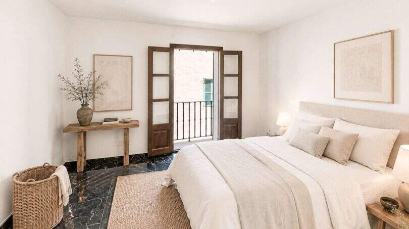 Helles Schlafzimmer mit Doppelbett, rustikalem Holzboden, schwarzem Marmor und Balkonzugang in Felanitx