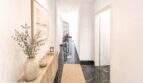 Eleganter Flur der Wohnung in Felanitx mit dunklem Marmorboden, Holzkommode und modernem Naturdekor.