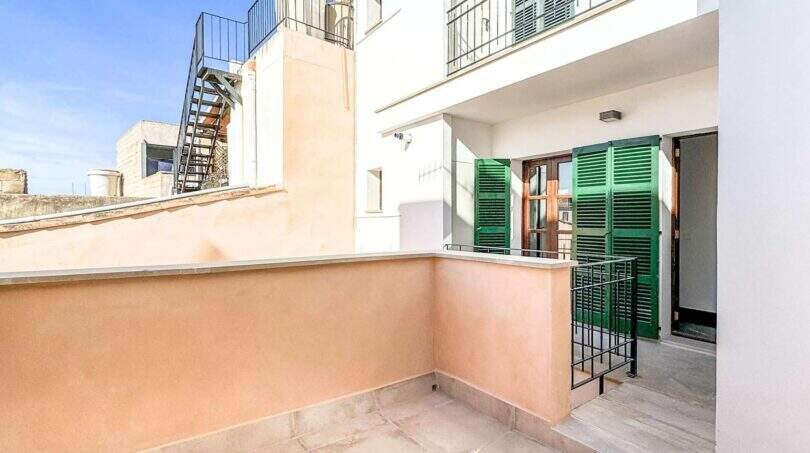 Sonnige Terrasse mit Fliesenbelag, grünen Holzläden und Treppenaufgang in Wohnung in Felanitx