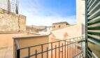 Balkon mit schwarzem Eisengeländer und grünen Holzläden mit Blick auf die Altstadt von Felanitx