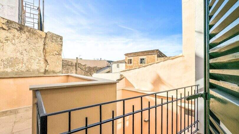 Balkon mit schwarzem Eisengeländer und grünen Holzläden mit Blick auf die Altstadt von Felanitx