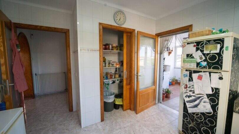 Küche mit Vorratsschrank, Kühlschrank, Wanduhr und Zugang zur Terrasse im Einfamilienhaus Porto Colom