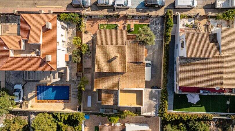 Drohnenaufnahme von Einfamilienhaus mit Terrakottadach, Pool und Garten in Portocolom aus der Vogelperspektive.