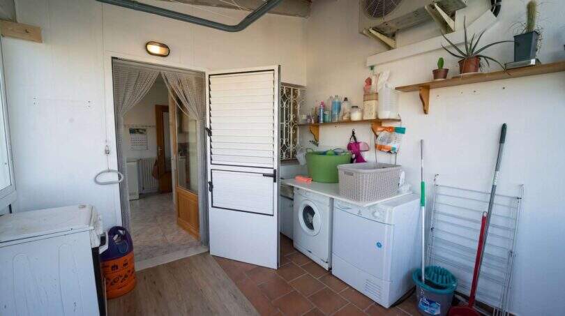 Hauswirtschaftsraum mit Waschmaschine, Trockner, Reinigungsutensilien und Regalablage im Einfamilienhaus Porto Colom.