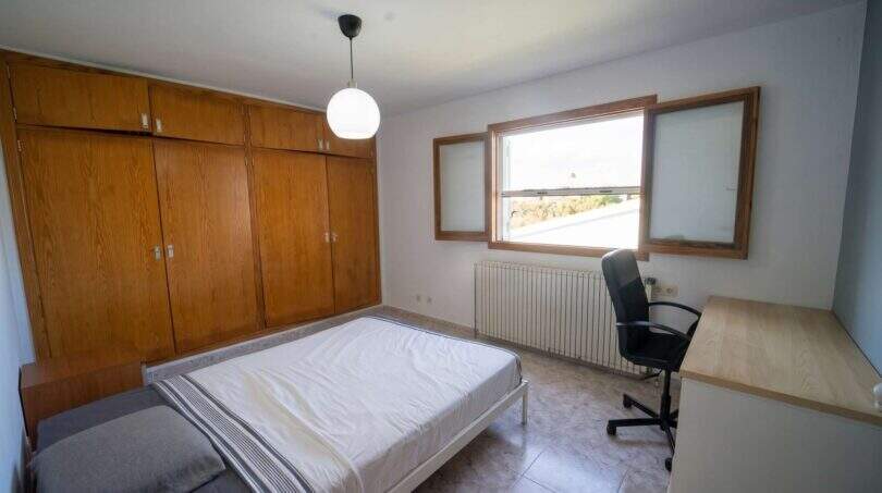 Helles Schlafzimmer mit Holzeinbauschrank, Doppelbett, Schreibtisch und Fenster mit Außenblick in Portocolom