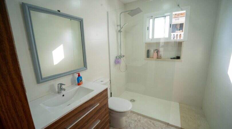 Modernes Badezimmer mit Glasdusche, WC und Holzwaschtisch im Einfamilienhaus Porto Colom