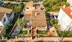 Luftaufnahme eines charmanten Einfamilienhauses in Porto Colom mit Terrakottadach, gepflegtem Garten und Pool.
