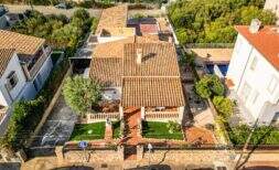 Aerial view of a charming single-family house in Porto Colom with terracotta roof, well-maintained garden and pool.