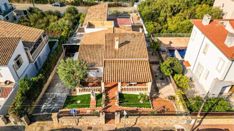 Luftaufnahme eines charmanten Einfamilienhauses in Porto Colom mit Terrakottadach, gepflegtem Garten und Pool.