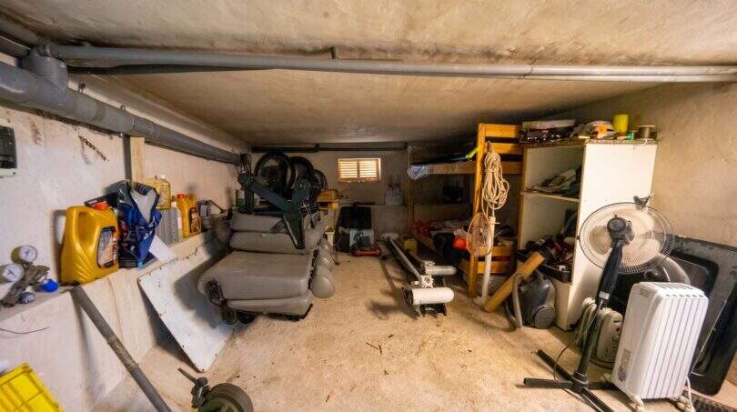 Vollgestellter Kellerraum mit Lagerregalen, Ventilator, Elektrogeräten und Rohren im Einfamilienhaus Porto Colom.