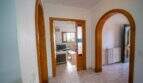 Heller Flur mit eleganten Rundbögen aus Holz, Marmorfliesen und Blick ins Wohnzimmer des Hauses in Porto Colom.