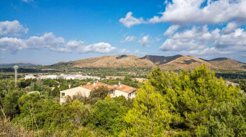Panoramablick auf Grundstück in Capdepera mit mediterraner Vegetation, Landhäusern und imposanter Bergkulisse.