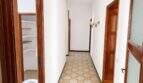 Langer Flur mit gemustertem Fliesenboden, Holztüren und Wandleuchte in renovierungsbedürftiger Wohnung in Palma