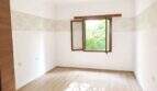 Leerer Wohnraum mit Holzparkett, Tapetenbordüre und geöffnetem Holzfenster mit Gartenblick in Palma