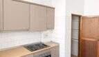 Küche mit Einbauküche, Elektroherd, Holzarbeitsplatte und Wandfliesen in renovierungsbedürftiger Wohnung in Palma