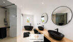 Modernes Badezimmer der Villa Sa Torre mit schwarzen Designwaschbecken, freistehender Badewanne und Glasdusche