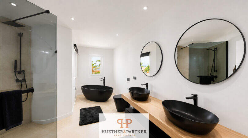 Modernes Badezimmer der Villa Sa Torre mit schwarzen Designwaschbecken, freistehender Badewanne und Glasdusche