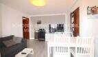 Salón luminoso con sofá gris, mesa de comedor blanca y TV en apartamento modernizado en Cala Ratjada