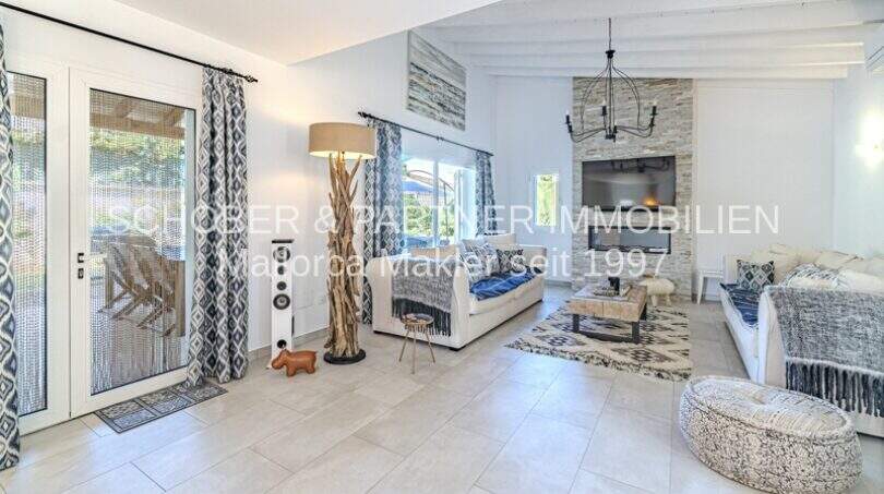 Helles Wohnzimmer der mediterranen Villa in Sa Coma mit blau-weißem Dekor, Naturstein und Terrassenzugang.
