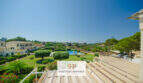 Balkon mit Holzverkleidung, Blick auf Gartenanlage mit Pool und mediterrane Landschaft in Porto Cristo Novo.