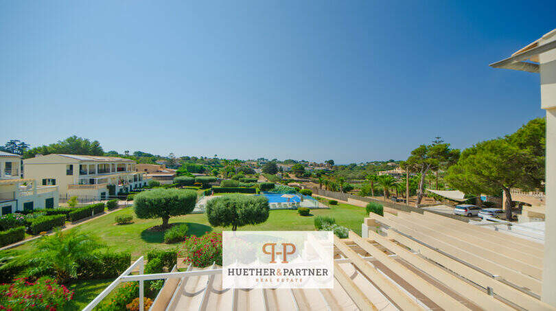 Balkon mit Holzverkleidung, Blick auf Gartenanlage mit Pool und mediterrane Landschaft in Porto Cristo Novo.